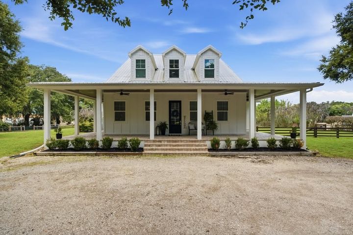 White farmhouse with a wraparound porch at 3651 Bateman Road in Alva